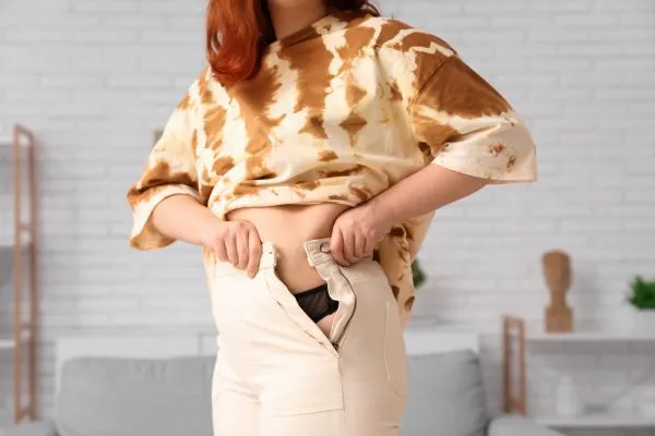 Image of woman trying to do her trousers up after pregnancy weight gain Canvey Island