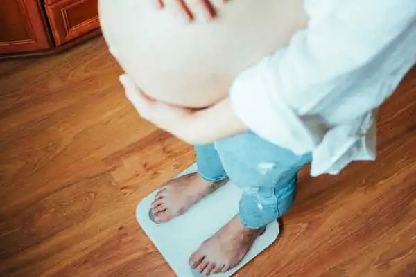 Image of woman weighing herself and experiencing weight gain through pregnancy Canvey Island